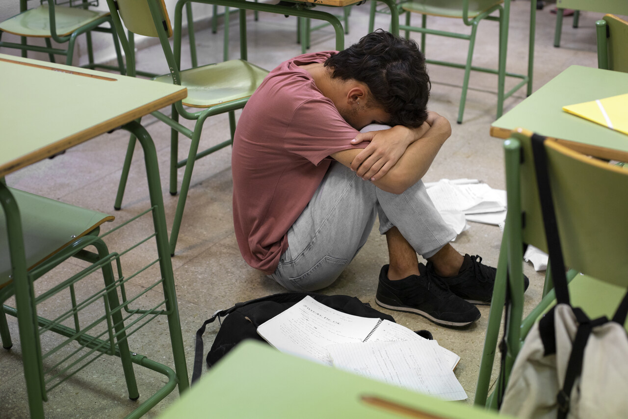 smutne dziecko siedzi na ziemi w szkole i płacze